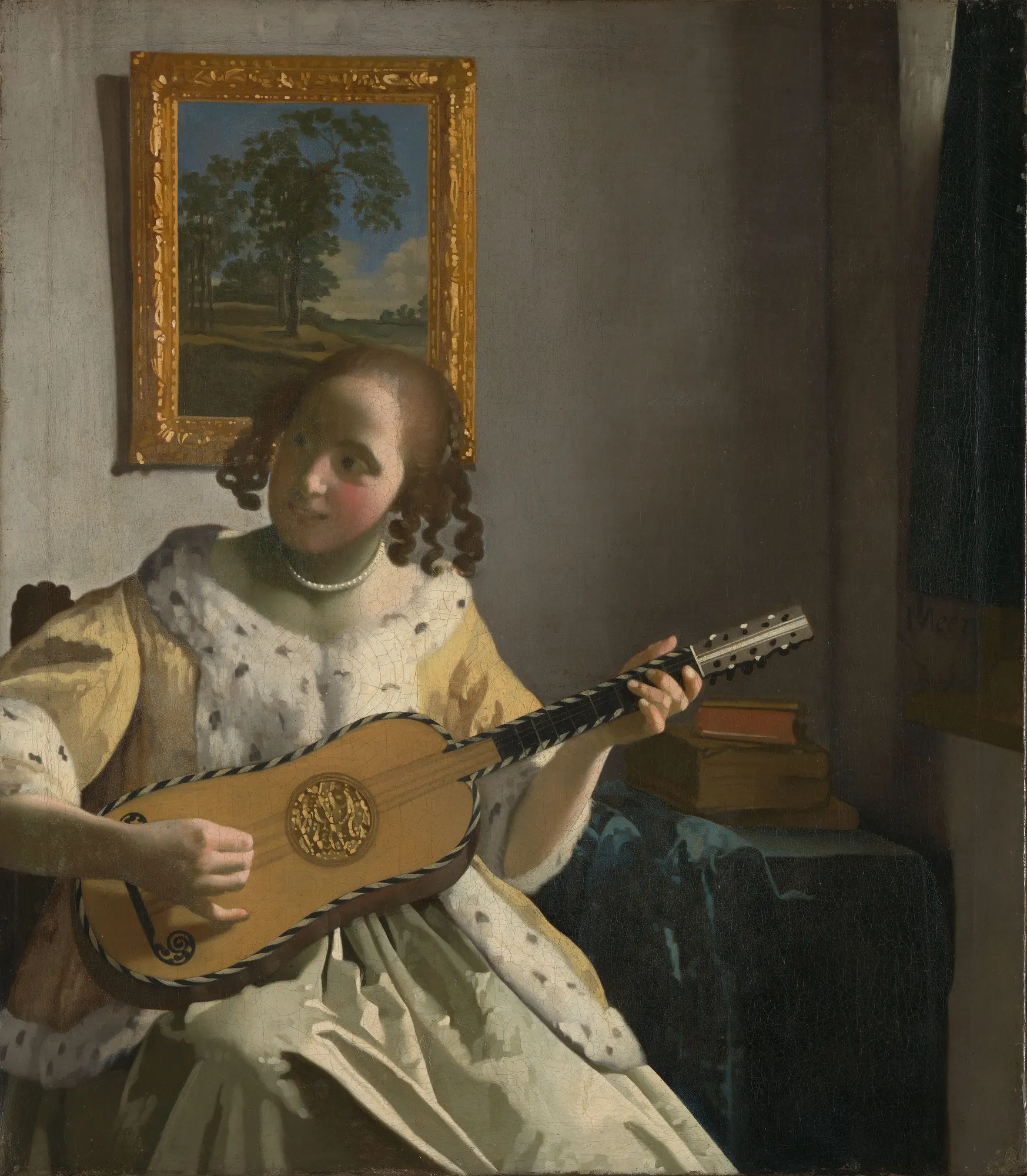 A young woman in a yellow ermine-trimmed jacket plays a guitar, glancing aside with a half-smile, in a sunlit Dutch interior.